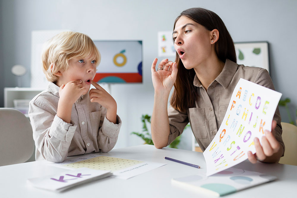woman-doing-speech-therapy-with-little-blonde-boy-low woman-doing-speech-therapy-with-little-blonde-boy-low